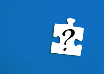 Top view of White Puzzle Piece with Drawn Question Mark on Blue background with copy space.