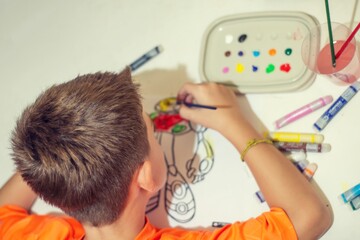 Niño en plano cenital pintando con témperas de colores