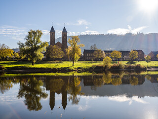 Fototapeta premium Ernst village and St Salvator church twin towers on Moselle river on a beautiful autumn sunset in Cochem-Zell, Germany