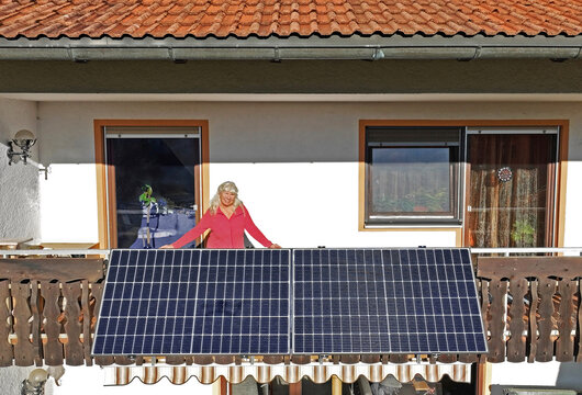 Eine Frau freut sich über die Solaranlage auf dem Balkon