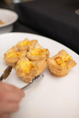 Person Using Tongs to Grab Egg Puff Pastry at a Brunch/Breakfast Buffet 