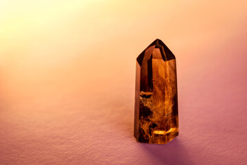 Smoky quartz crystal point with phantoms isolated on a pink background