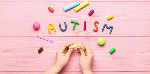 Child's hands with plasticine and word AUTISM on pink wooden background - obrazy, fototapety, plakaty