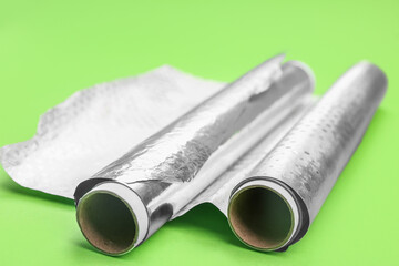 Rolls of aluminium foil on green background, closeup