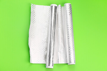 Rolls of aluminium foil on green background