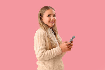 Little girl using mobile phone on pink background