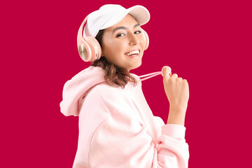 Young woman in headphones on pink background