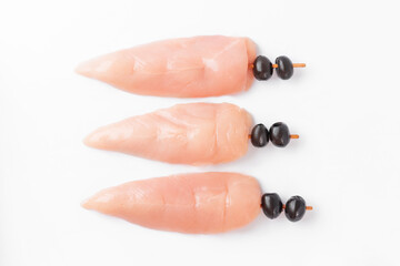 Raw uncooked Chicken meat, kebab on skewers on a white background .skewers of raw meat and vegetables.raw chicken inner on skewers with olives on a white background.