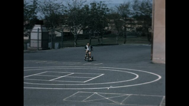 Riding Trike Playground 1968 - A three years old boy rides his trike in the school playground