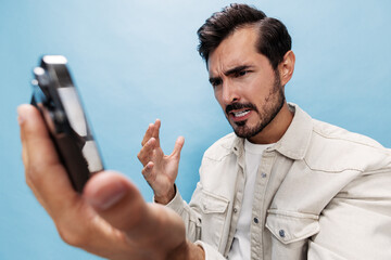 Portrait of a stylish brunette man looking at the phone blogger with a beard of anger and...