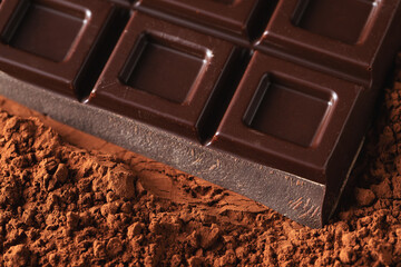 Dark and milk chocolate with nuts on a dark background sprinkled with cocoa powder.