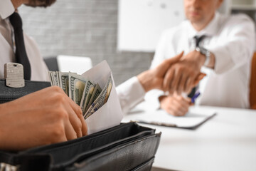 Business men with bribe shaking hands in office, closeup