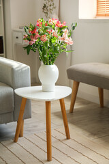 Vase with fresh alstroemeria flowers on table in room