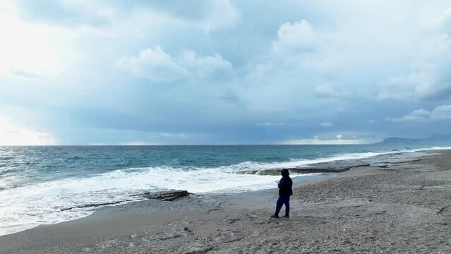 Meditative woman standing on beach and admiring the sea cinematic fly shot