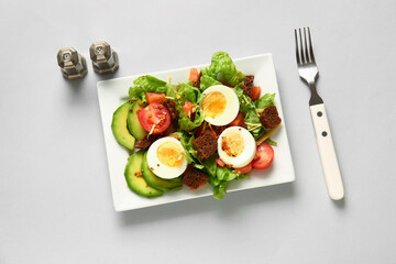 Plate of delicious salad with boiled eggs and salmon on grey background