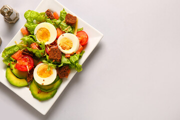 Plate of delicious salad with boiled eggs and salmon on grey background