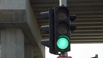 close up view of traffic light that turns green under bridge on pole. Traffic control in city at...