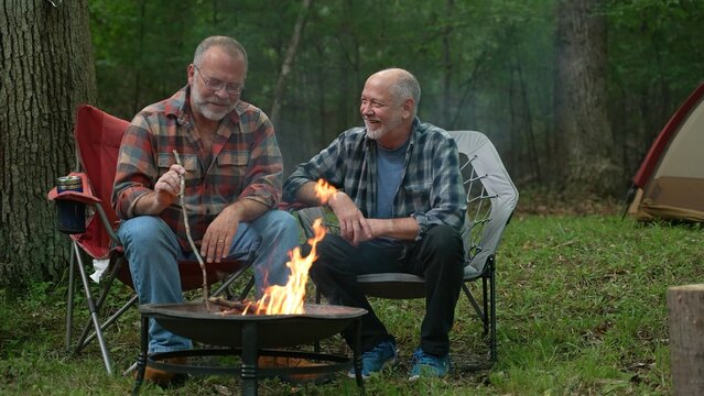 Closeup of two gay men in front of campfire laughing and smiling celebrating pride. - Powered by Adobe