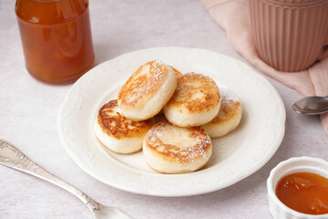 Plate with tasty cottage cheese pancakes and jam on light table