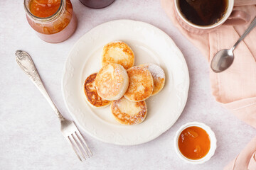 Plate with tasty cottage cheese pancakes and jam on light table