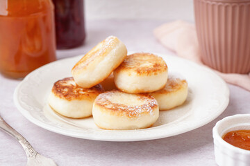 Plate with tasty cottage cheese pancakes on light table, closeup