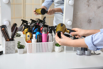 Hairdresser with hair dryer at table in beauty salon, closeup