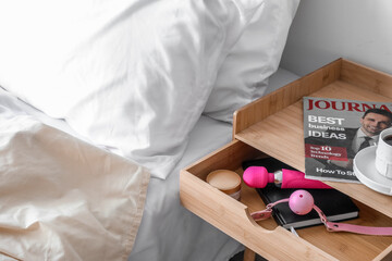 Open drawer with sex toys, notebook and cream in bedroom, closeup - obrazy, fototapety, plakaty