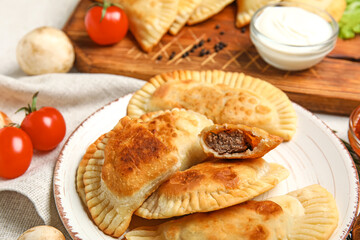 Plate with tasty meat empanadas on table, closeup