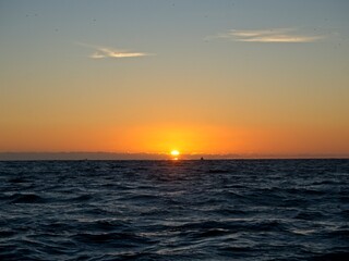 Obraz premium The sun sets over the Pacific Ocean as we sail around the end of the Baja California Peninsula near Cabo San Lucas