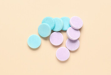 Obraz na płótnie Canvas Blue and lilac soluble tablets on beige background