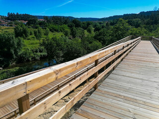 Wooden walkways to walk in a tourist landscape of Portugal in Europe, showing nature around with trees and blue sky.