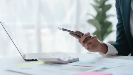 Using mobile cellphone, Close up hands of asian bookkeeper female working with stack of papers and balance sheet with bureaucracy hardworking in office desk.