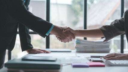 Shaking hands, Auditor and the company's bookkeeper jointly review the balance sheet and assets, liabilities and equity information in the quarterly report, bookkeeping concept.