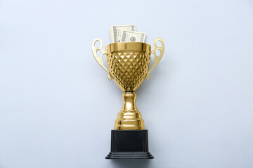 Gold cup with money on light background