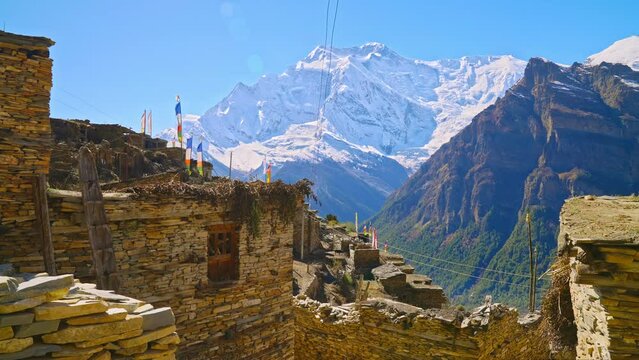Snow Covered Himalayan mountain peaks by ancient village of rustic stone buildings, Annapurna, Nepal