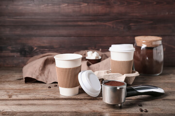 Scoop of coffee powder and cups on wooden table, closeup
