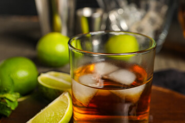 Glass of rum with ice, mint and lime on table, closeup