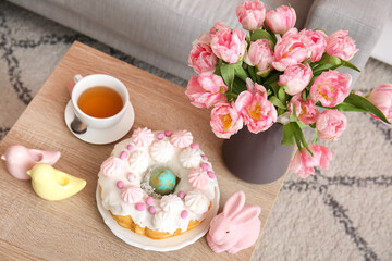 Easter cake, bunny, porcelain quails and vase with tulip flowers on table in living room
