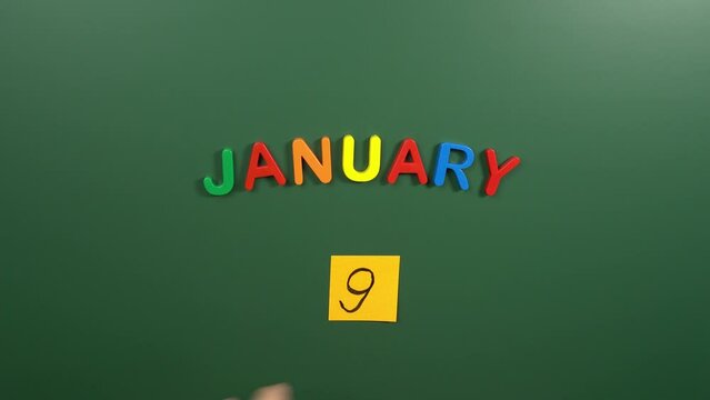 Hand sticking a sticker 9 January calendar day on school board. 9 date of January. Ninth day of January. 9th date number. 9 day calendar. Nine date
