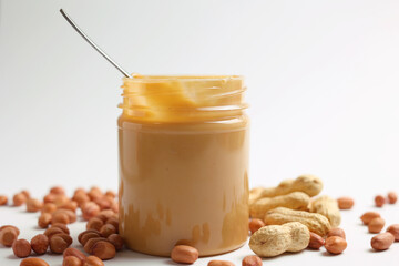 peanut butter and raw peanuts on a light background
