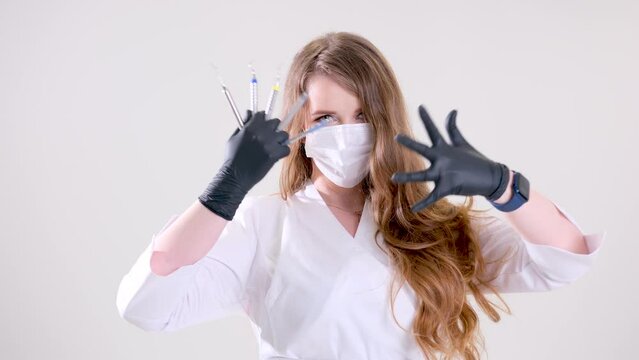Beautiful woman dentist in black suit with a white mask with flowing hair holds in her hands scaler and curette Hand stretched forward selective focus bright photo of gorgeous woman