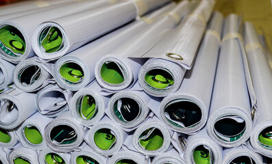 close up of a bunch of banners rolled up in a room in the printing industry. stacks of products are...