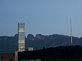 Towering high rises peek over the Loma Larga, a steep hill that divides the cities of Monterrey and San Pedro Garza García, with the Sierra Madre Oriental mountain range in the background