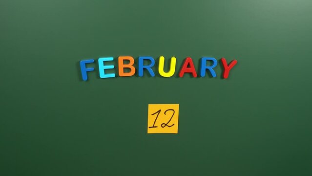 Hand sticking a sticker 12 February calendar day on school board. 12 date of February. Twelfth day of February. 12th date number. 12 day calendar. Twelve date. Darwin