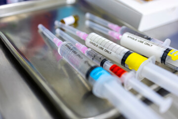 A medical syringe with a colorful tag label on stainless tray in hospital.Drug preparation for patient sedation before surgery with blur background.Close up macro photo of syringes with medicine.