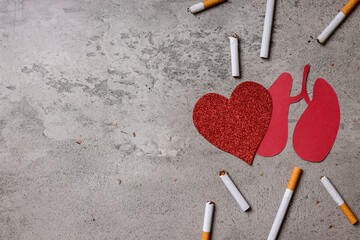 Quit smoking for better health concept. Cigarettes with red heart and lungs paper shape on gray...
