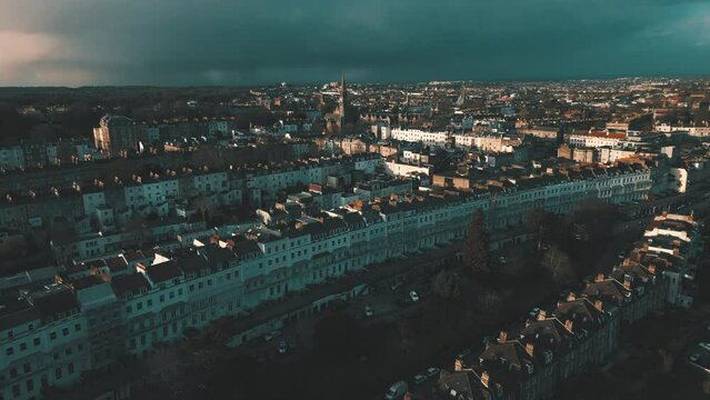 Aerial drone shot of a church spire above rooftops in Clifton, Bristol, with dark storm clouds in the sky