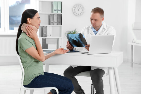 Doctor with neck MRI image consulting patient in clinic