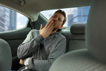 Sleepy tired man yawning in modern car