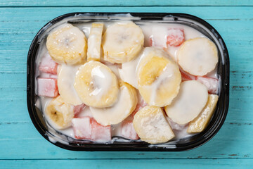 top view fresh banana slices and watermelon blocks with yogurt at horizontal composition